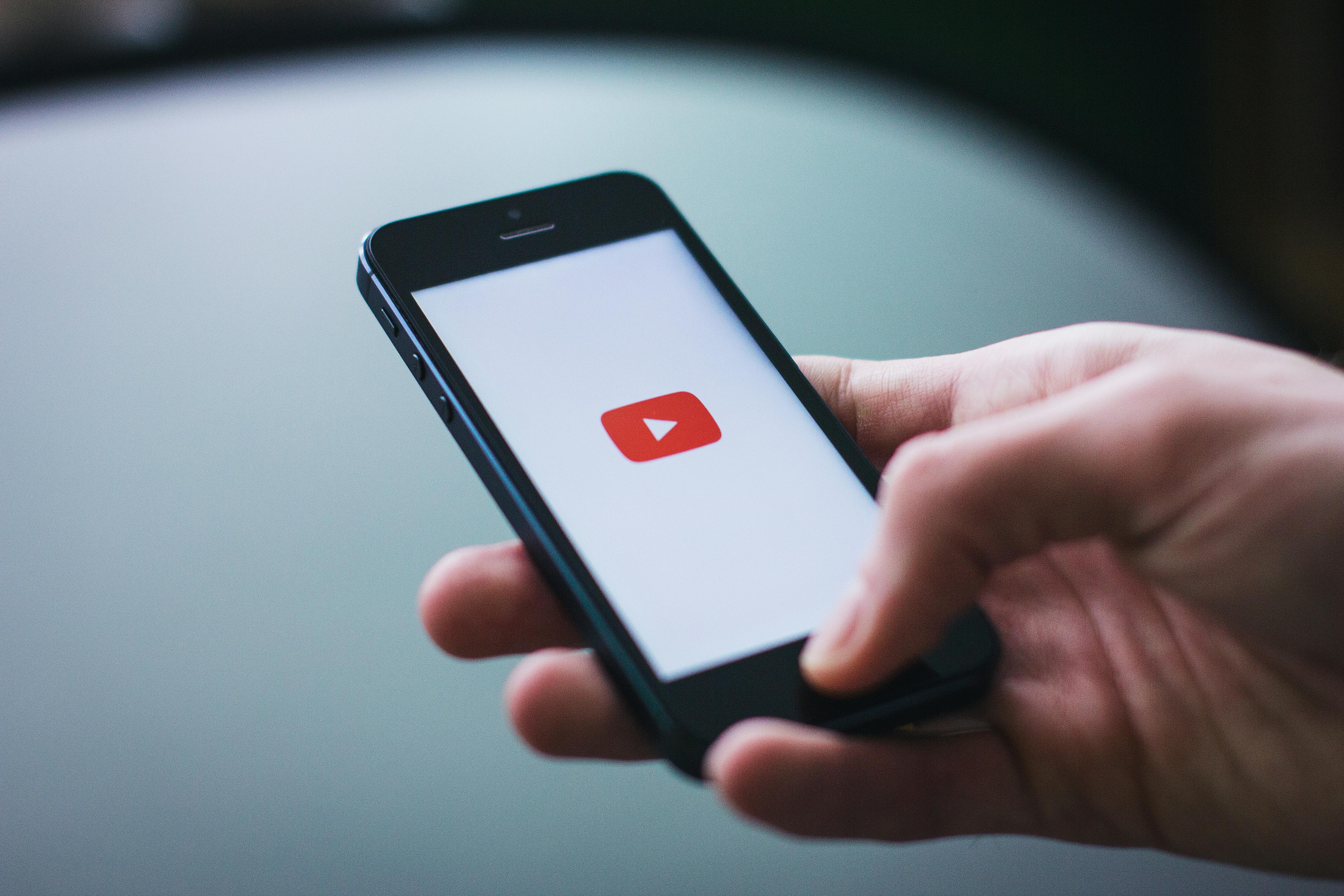 YouTube marketing tips - man holding a phone opening up the youtube app